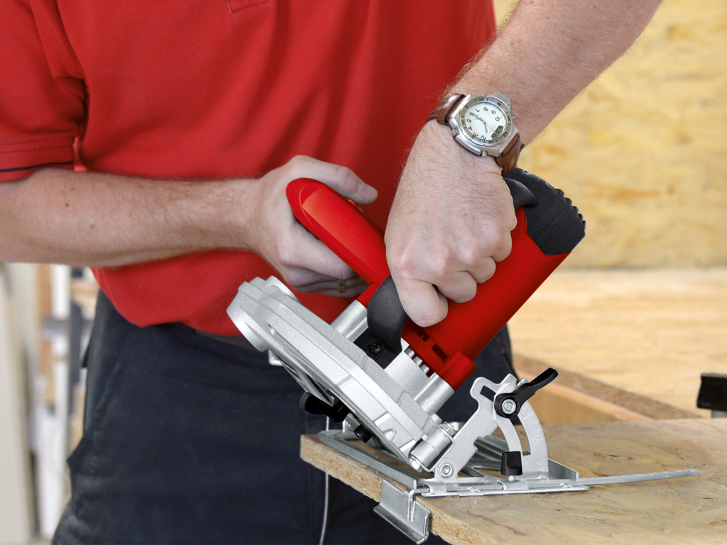 a man cuts a wooden board with a hand circular saw