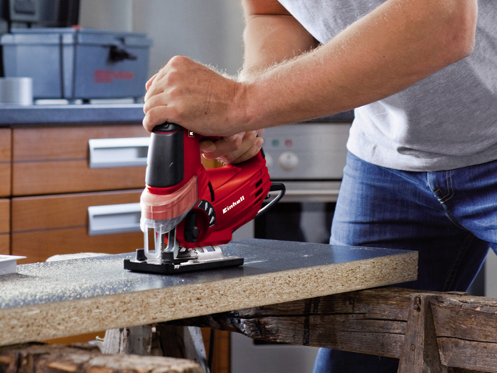 a man cuts a wooden board with a jigsaw