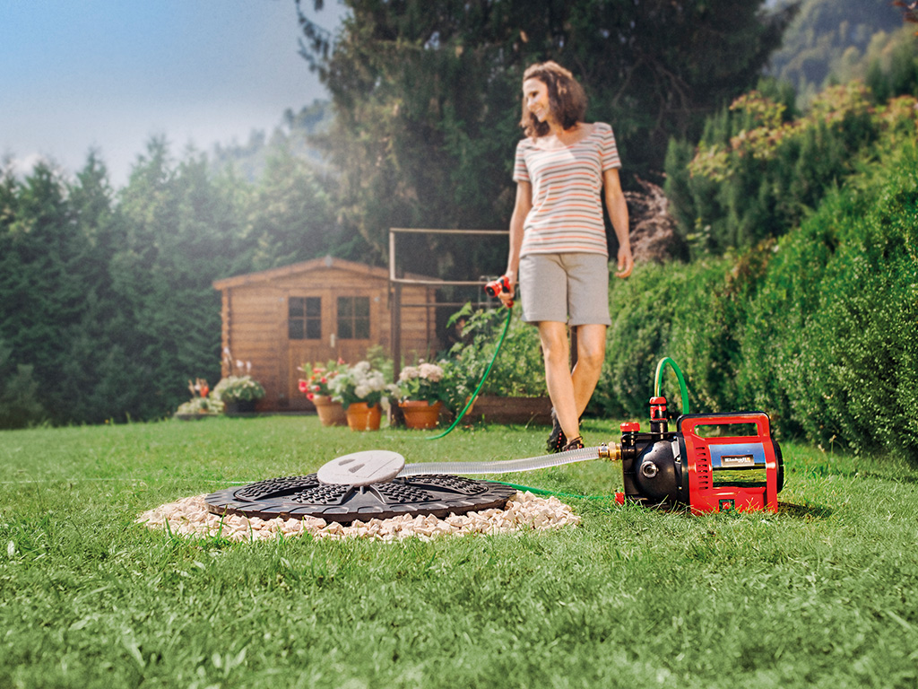 Woman waters flowers with water from the pump