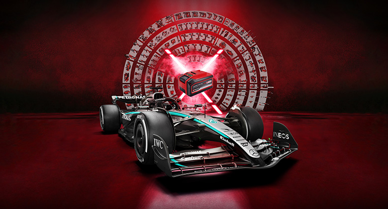 Trkaći automobil Mercedes-AMG PETRONAS Formula 1 postavljen je u odnosu na živahnu crvenu pozadinu, s Einhell baterijom u središtu. Logotipi Einhell-a i Mercedes-AMG PETRONAS F1 Tima prikazani su u donjem desnom uglu.