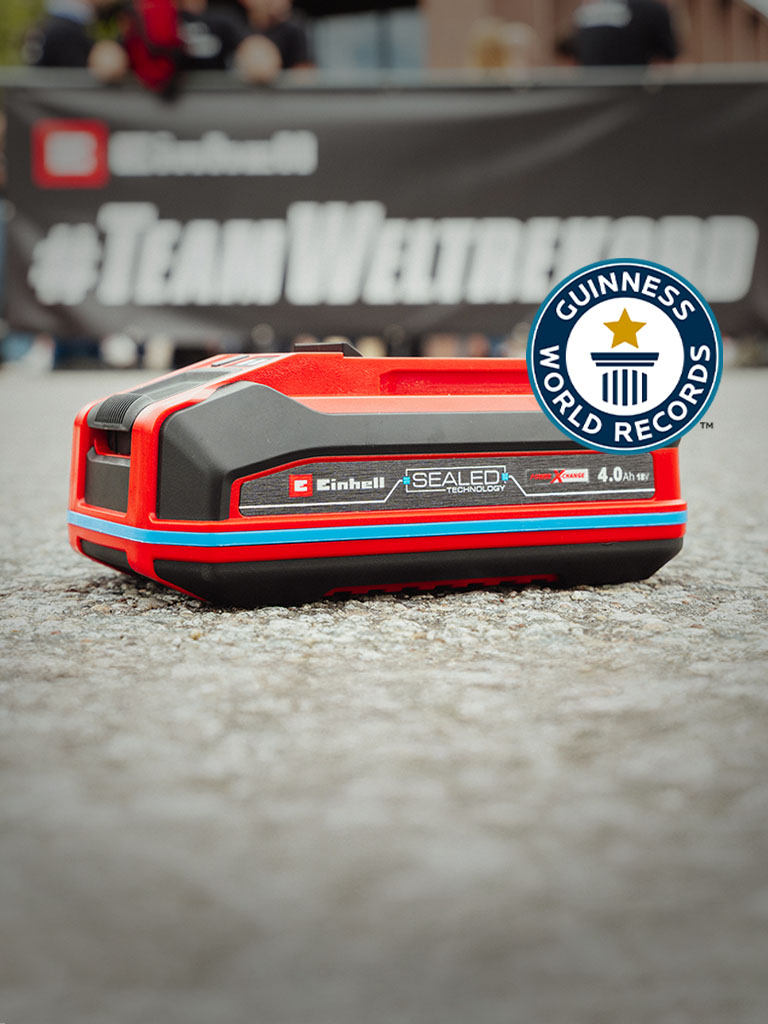 Einhell SEALED Power X-Change 4.0 Ah baterija postavljena na asfaltu, sa logom Guinness World Records "Record Holder" sa desne strane.