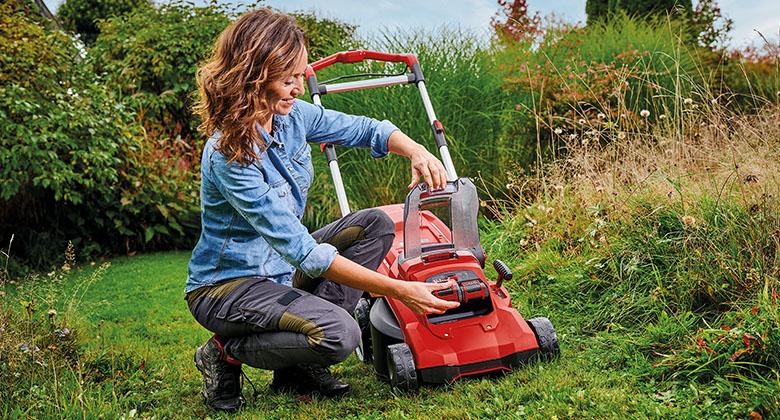 A woman inserting the Power-X-Change battery into the lawn mower 